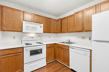 A kitchen with white appliances and wooden cabinets.